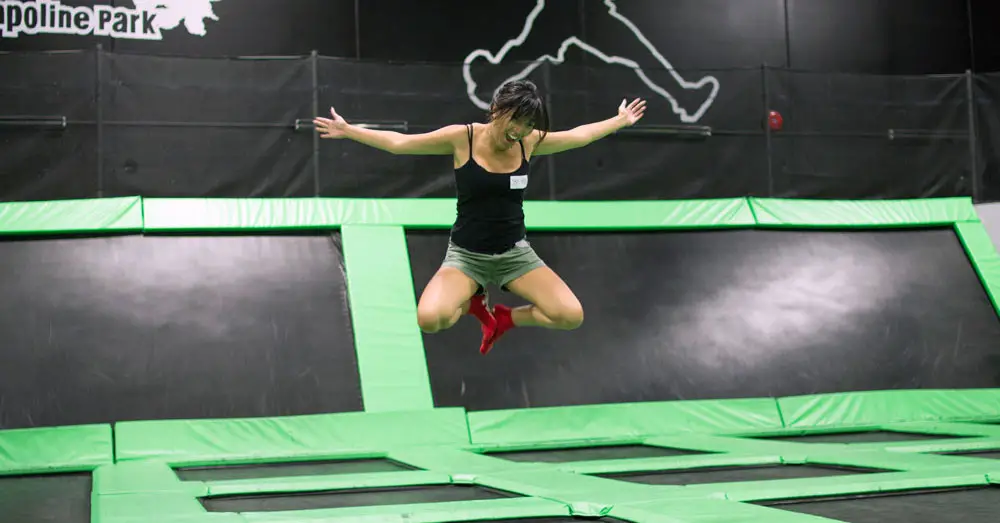 A woman enjoying jumping at a trampoline park.